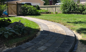 Paving stone walkway curving to fence gate